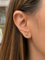 A close-up of a person's ear wearing a small gold turtle stud earring.