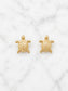 A pair of small gold turtle stud earrings displayed on a white marble surface.