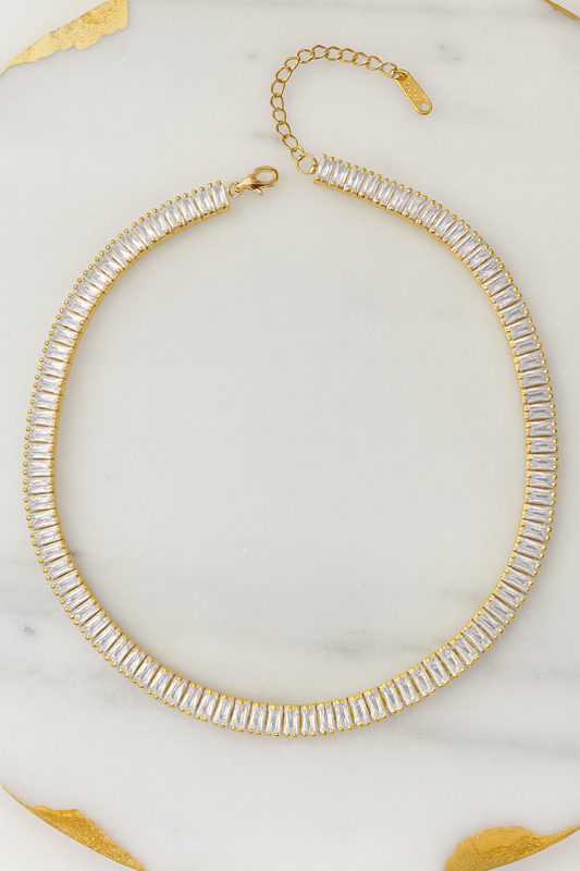 Gold and clear beaded necklace on a marble surface