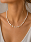 Pearl necklace worn by a person with a neutral background