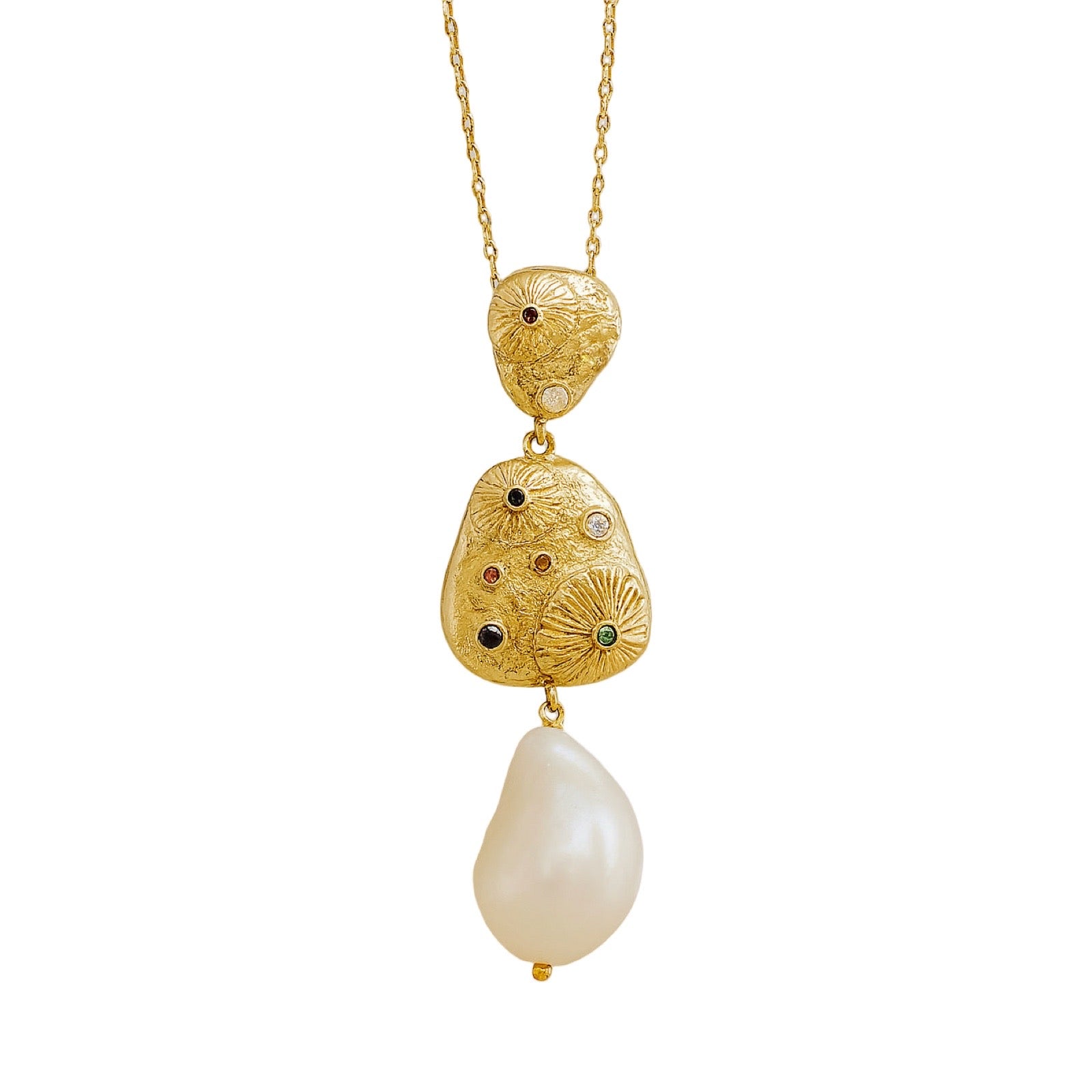 A gold pendant necklace featuring three stacked, textured gold charms with tiny colored gemstones and a large, teardrop-shaped white baroque pearl hanging below, set against a plain white background.