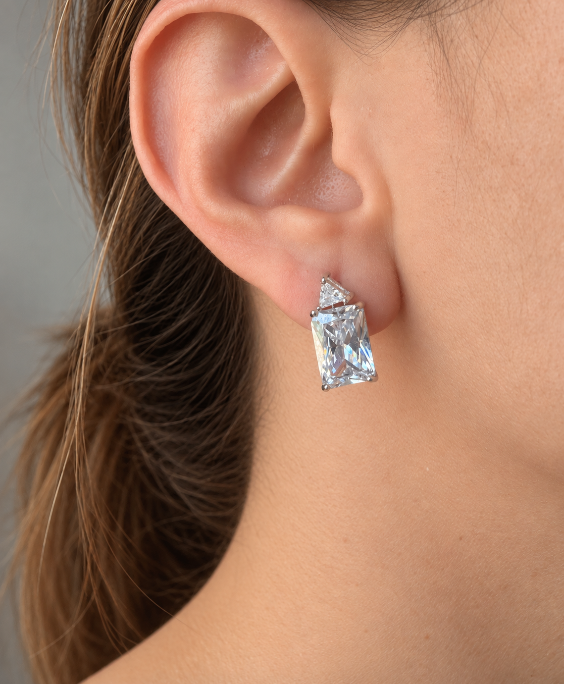 Sterling silver rectangular and triangular cubic zirconia stud earrings worn on ear
