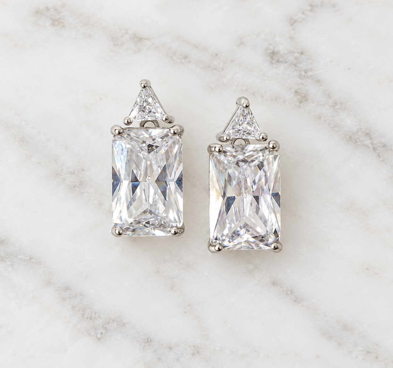 Sterling silver rectangular and triangular cubic zirconia stud earrings on white marble